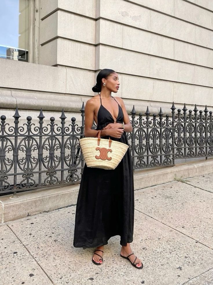 Black halter maxi dress complemented by a LOEWE straw bag